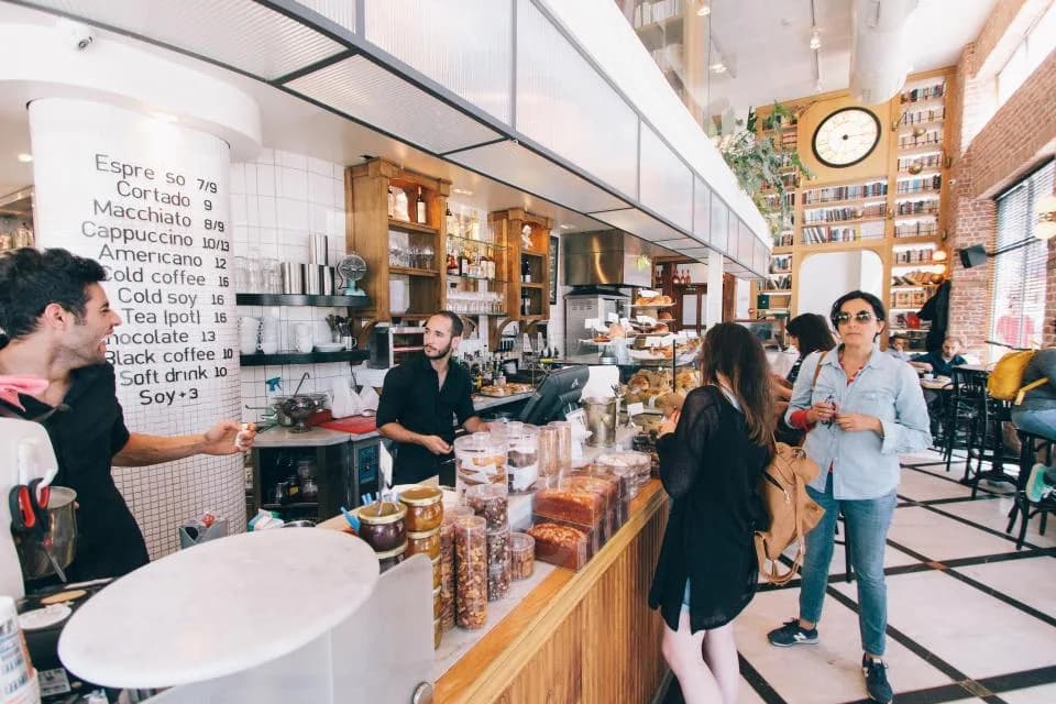Des clients au comptoir d'un café, servis par l'équipe